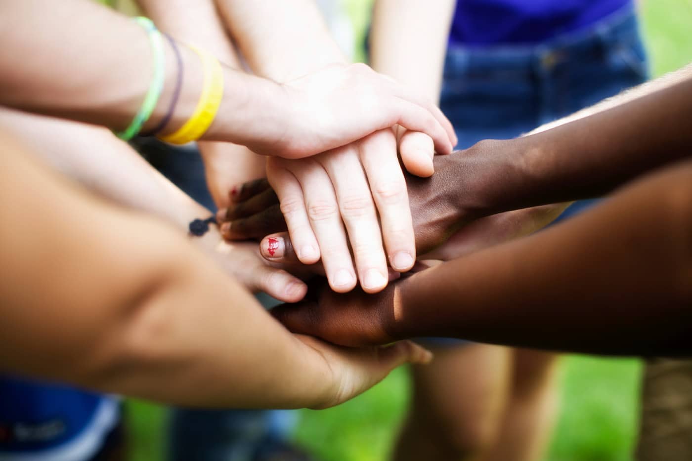 People with different skin tones stack hands on top of one another's