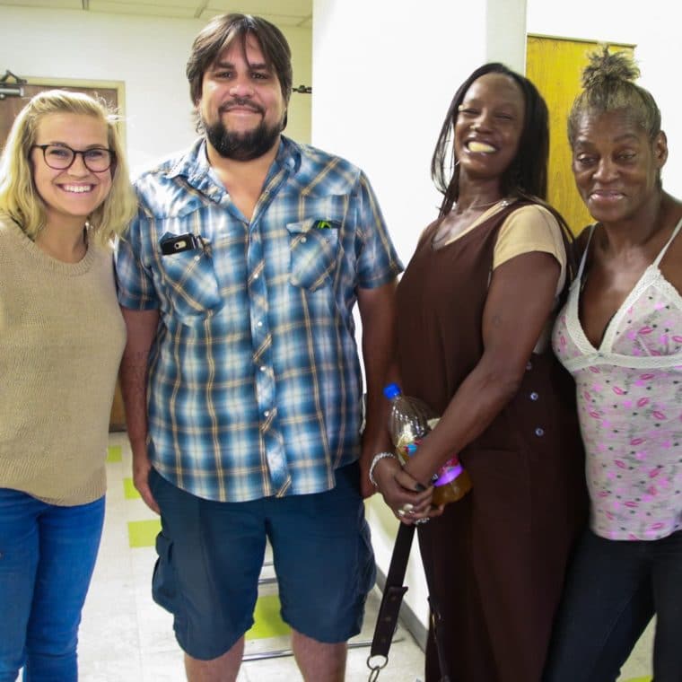 Group of three women and one man smiling at the camera