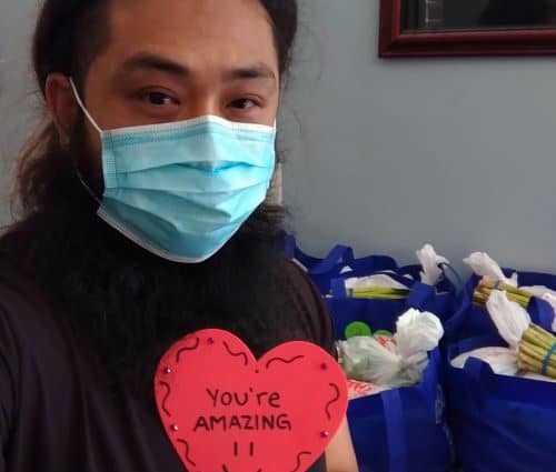 Young man wearing mask and holding a paper heart