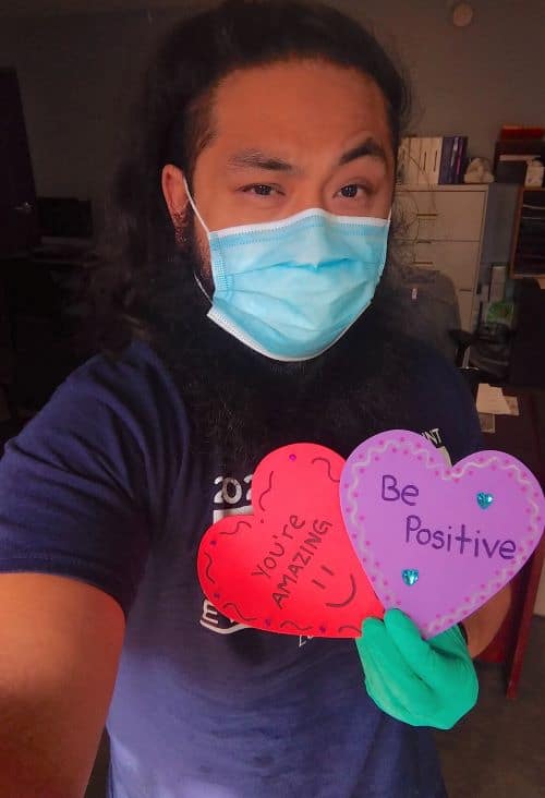Young man in mask holding paper hearts