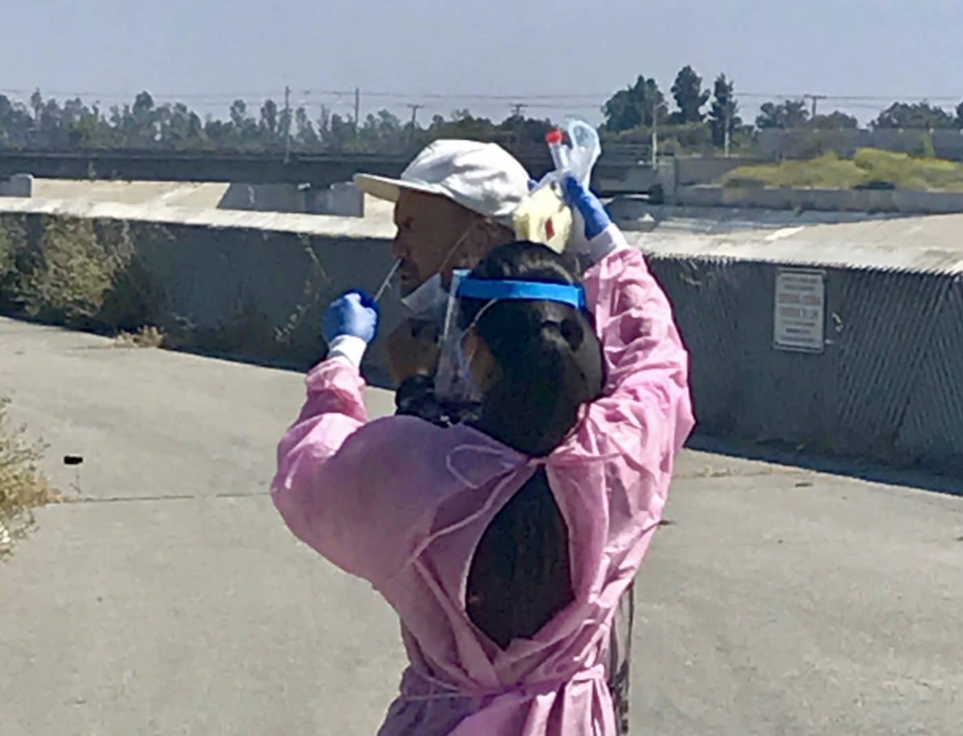 Female nurse administering Covid test to man on street