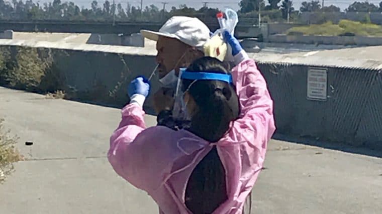 Female nurse administering Covid test to man on street
