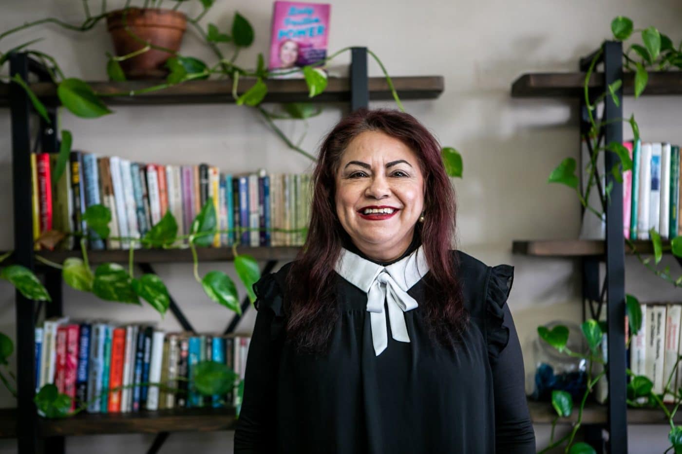 MHALA Member Diana in front of bookcase at Wellness Center