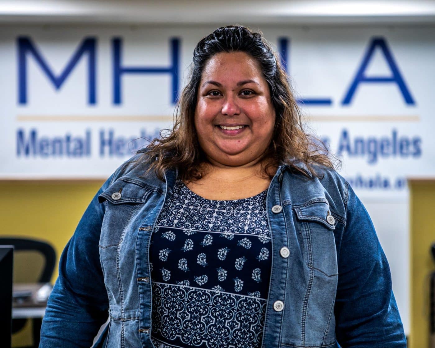MHALA member in jean jacket standing in front of MHALA banner.