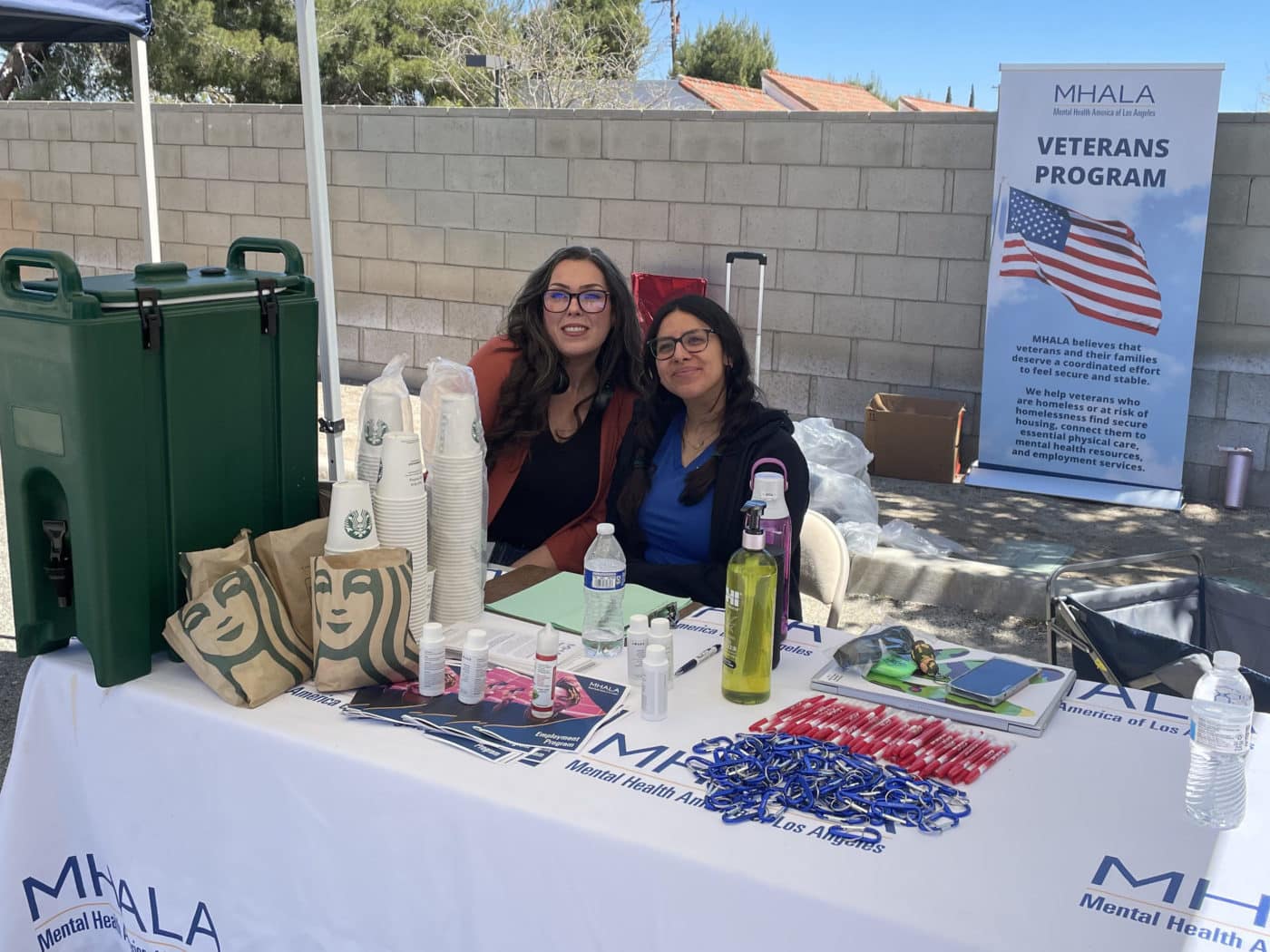 Two staff from MHALA's Veterans Program sit at outside table.