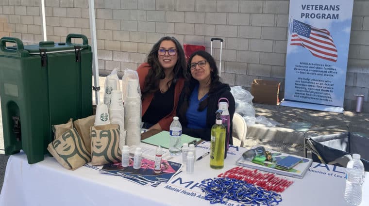 Two staff from MHALA's Veterans Program sit at outside table.