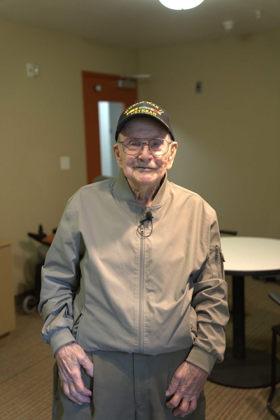 Male World War II Veteran in tan jacket, standing in room