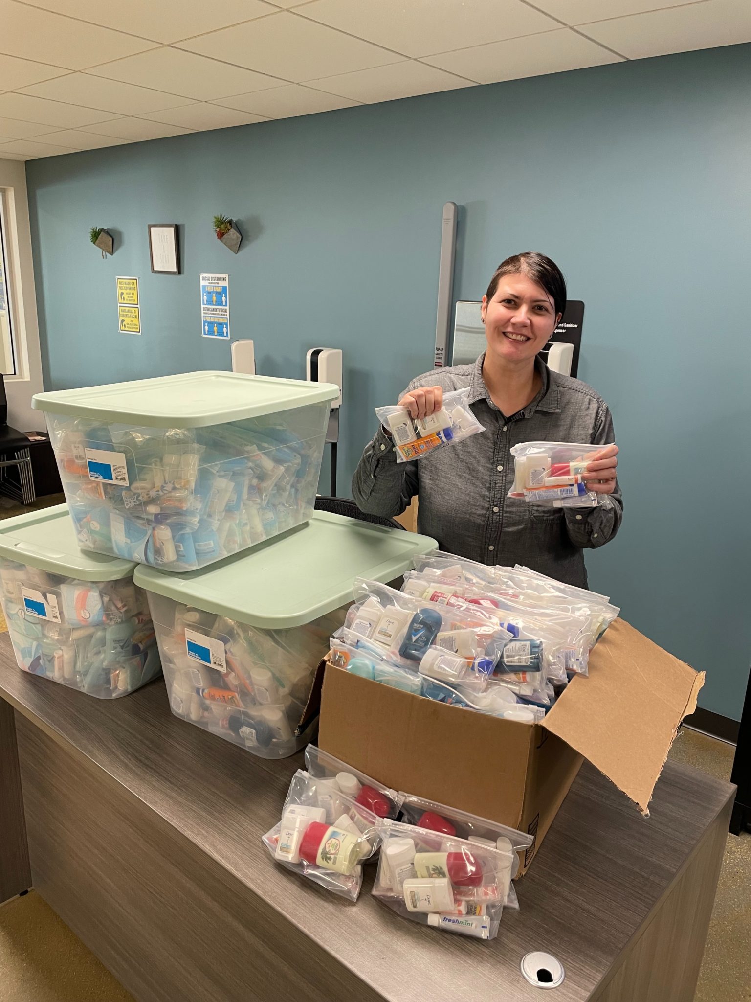 Woman standing behind boxes of donated goods.