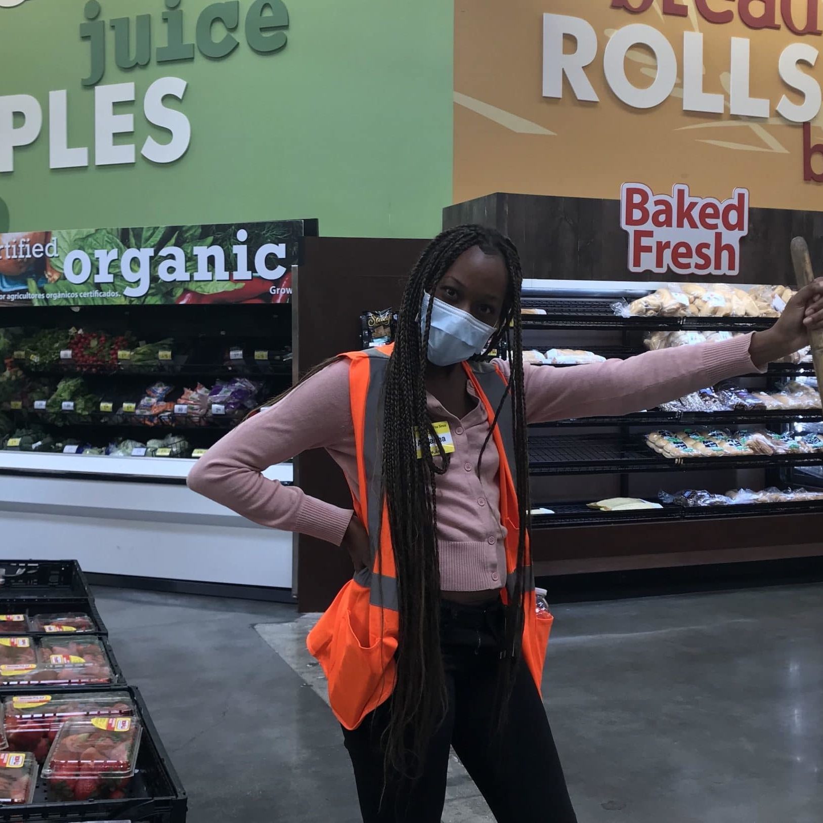 Areanna Young woman in grocery store wearing a mask and holding a broom