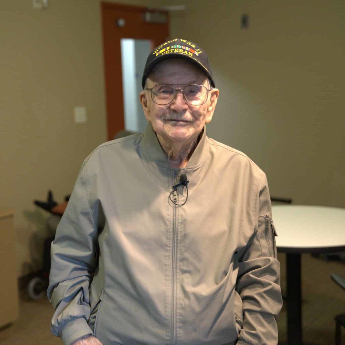 Male World War II Veteran in tan jacket, standing in room