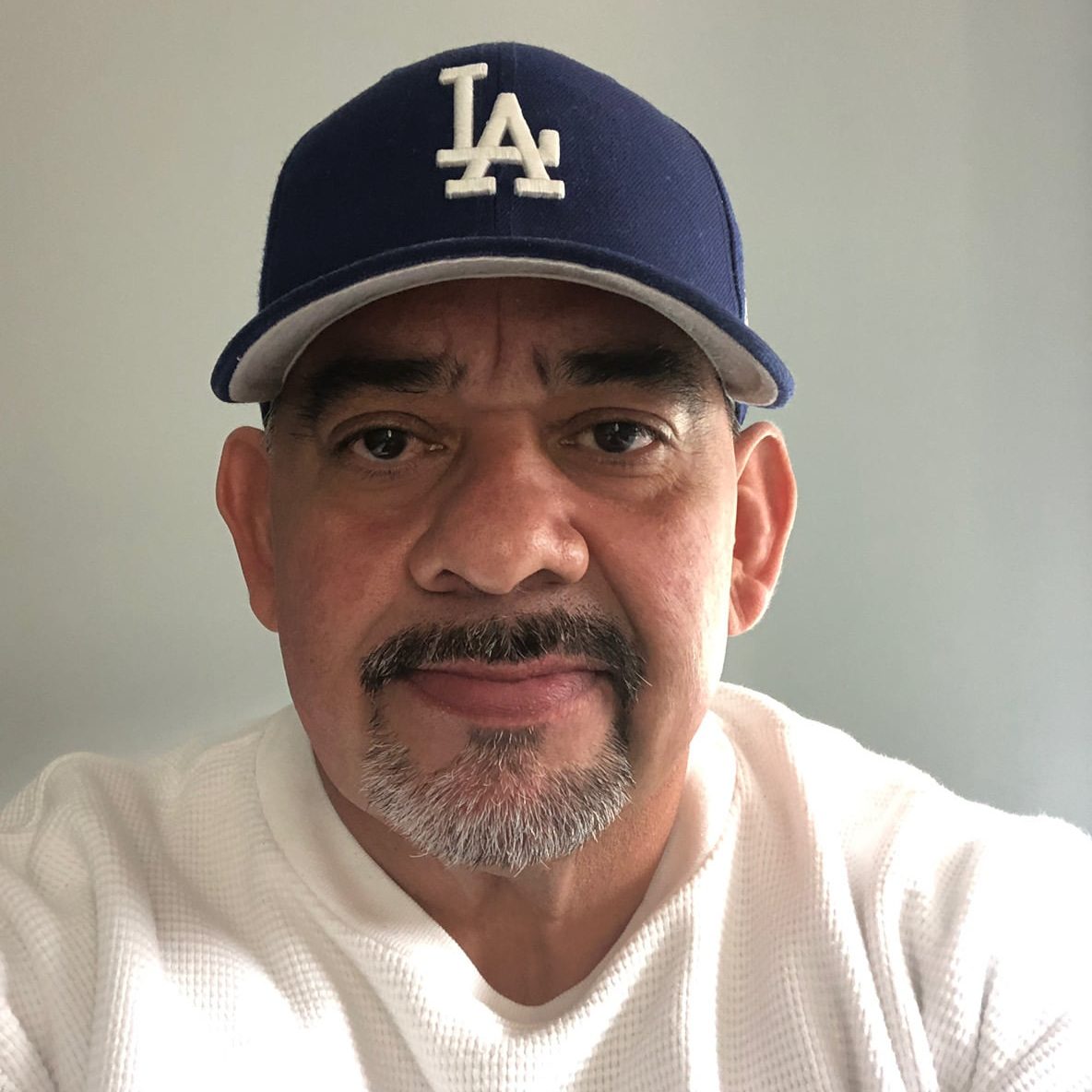 Sal R Headshot Man with goatee in a white t-shirt and LA baseball cap.
